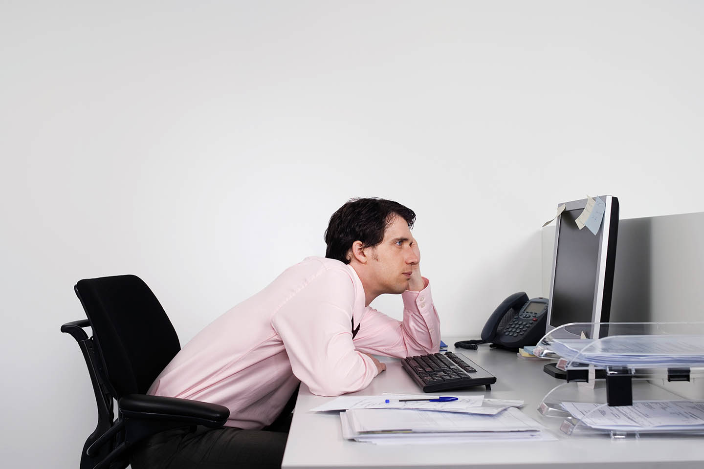 A bored looking man slouching at his desk