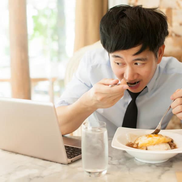 A man eating food while looking at a computer