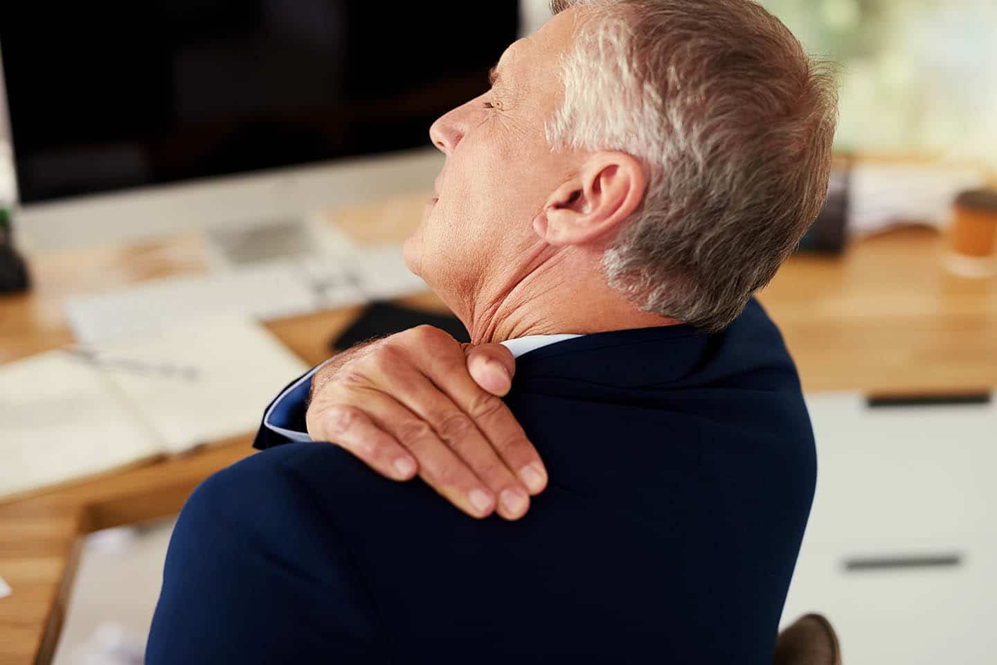 A man rubbing the back of his shoulder