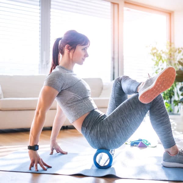 A woman stretching using a foam roller