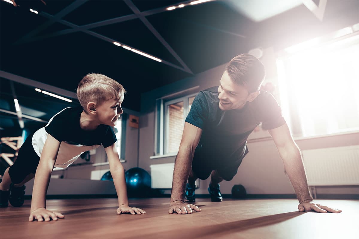 A man and boy exercising together in a gym