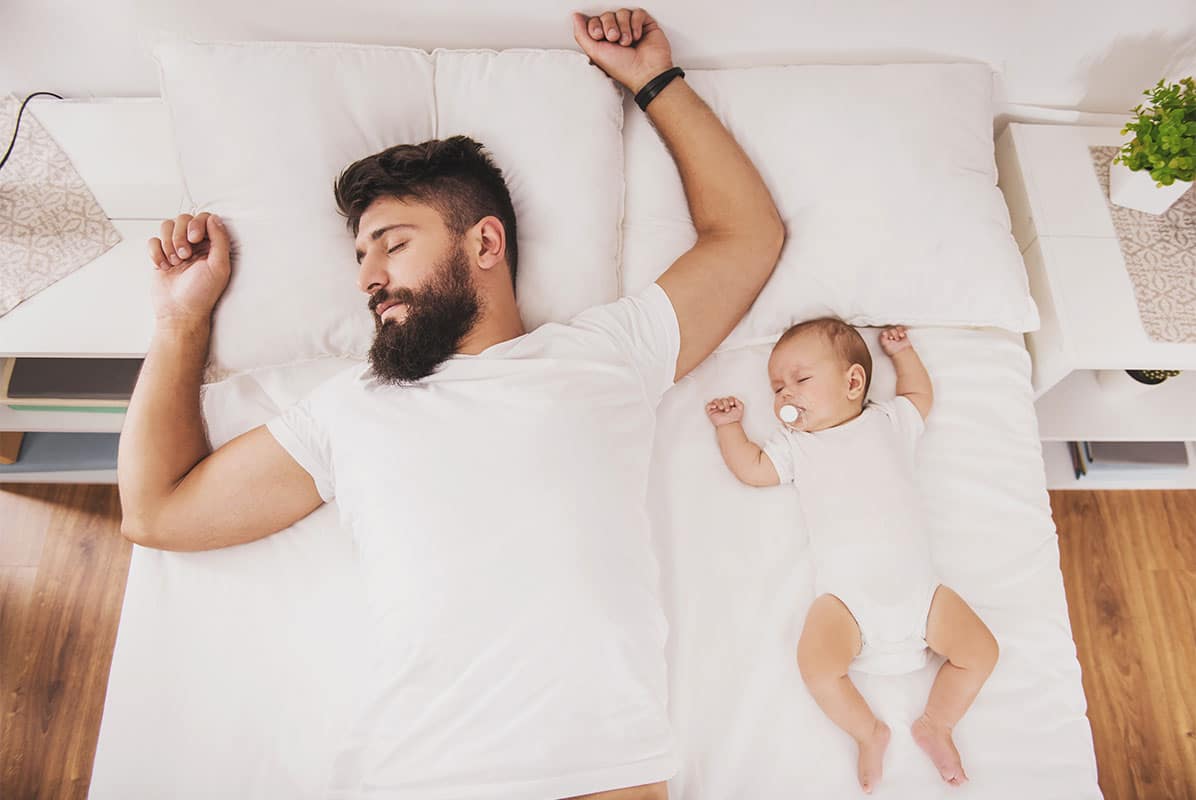 A man and a baby sleeping in bed together