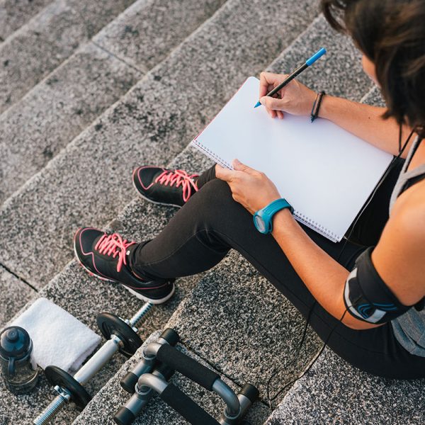 A woman writing in a journal before starting her workout