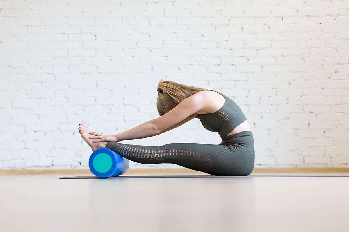 A woman using a foam roller to perform stretches