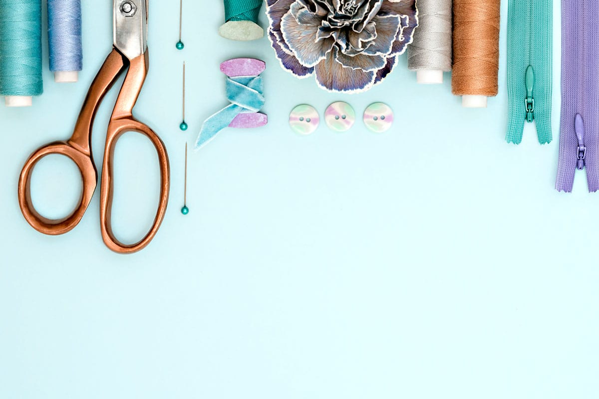A collection of sewing tools and supplies on a blue background