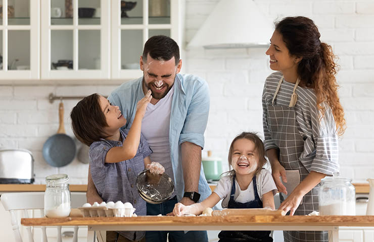 Family of four laughing in the kitchen